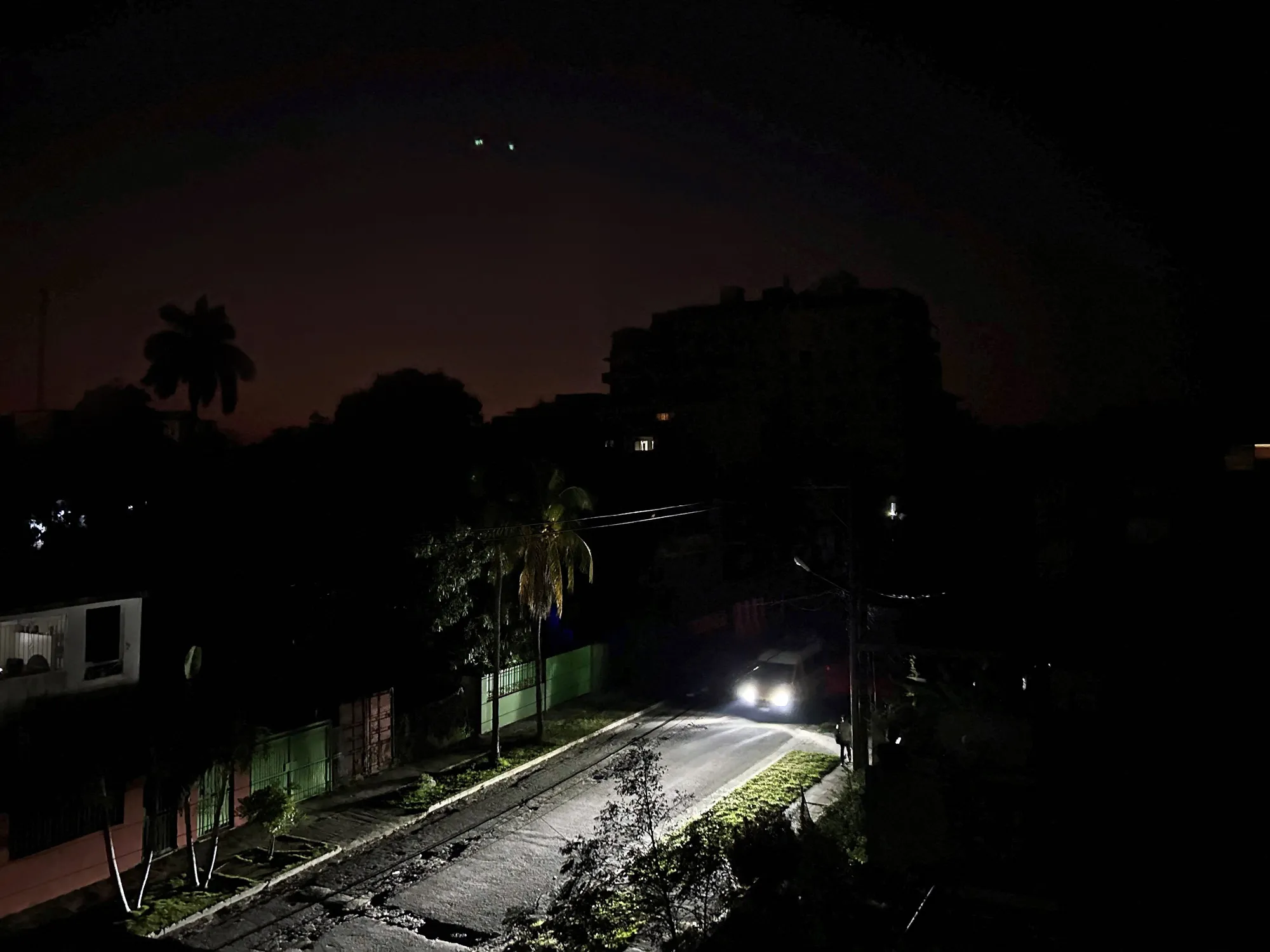 car-headlights-illuminate-a-residential-street-at-night-during-a-power-outage-in-cuba.webp